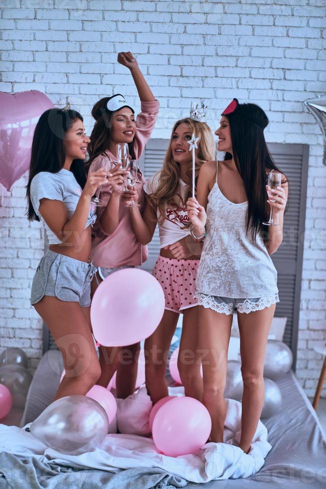 Happy to be around. Full length of four attractive young smiling women in pajamas toasting each other while having a slumber party photo
