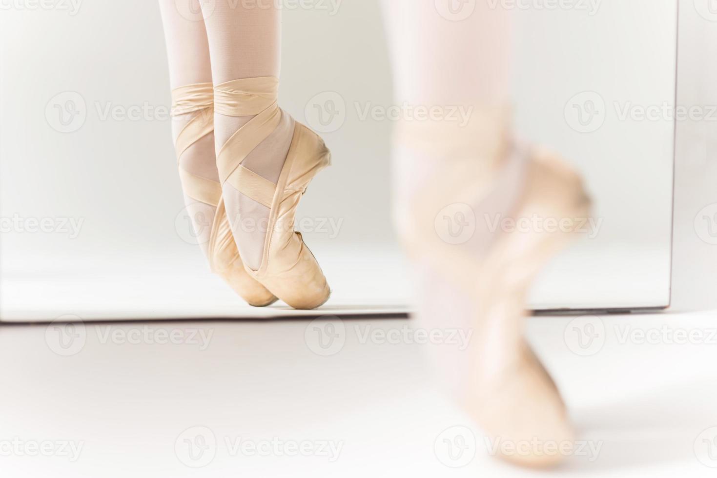 Dancing in Pointe. Close-up of ballerina legs in slippers standing against mirror photo