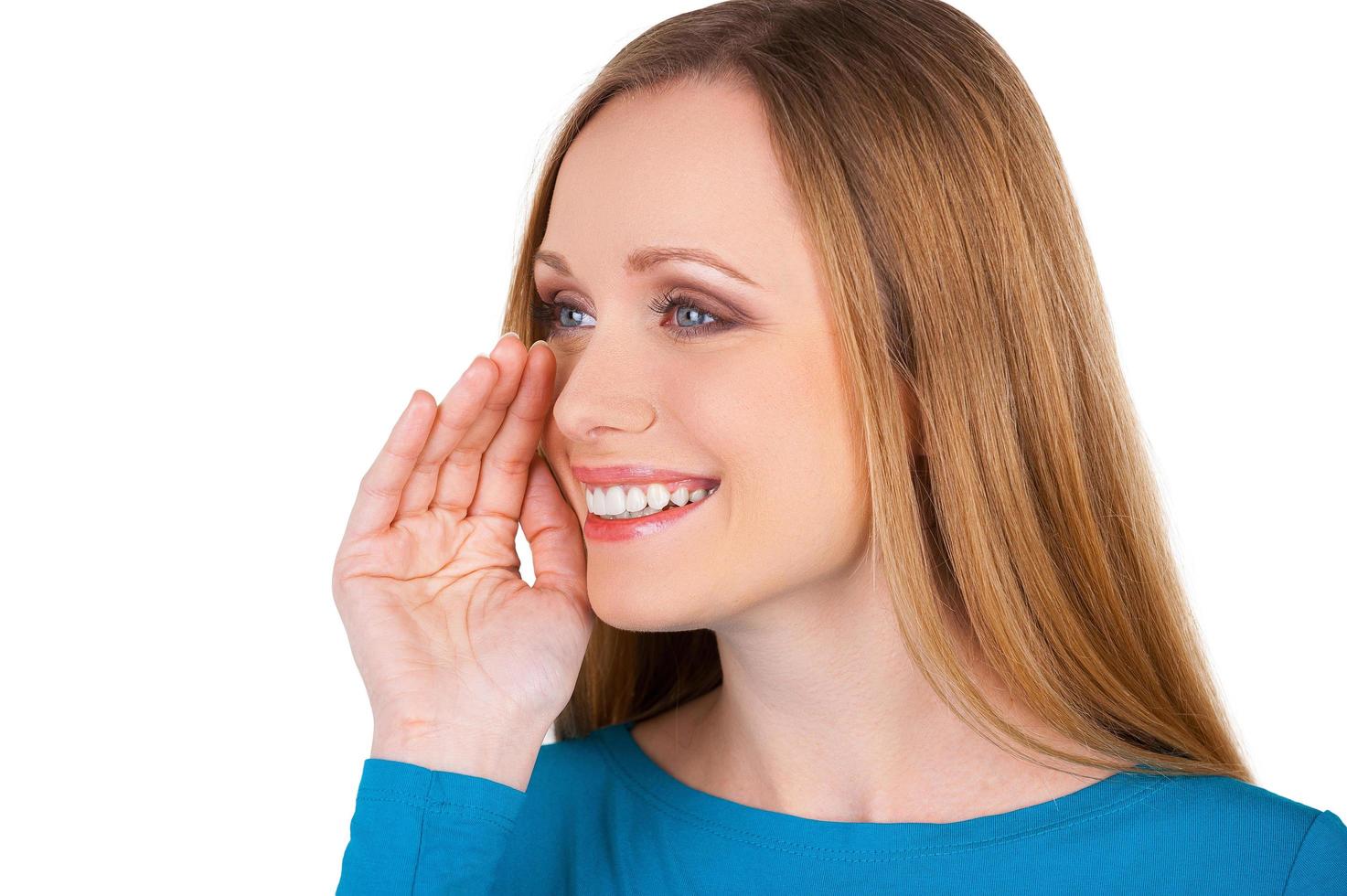 Telling good news. Cheerful young woman holding hand near mouth and smiling while isolated on white photo