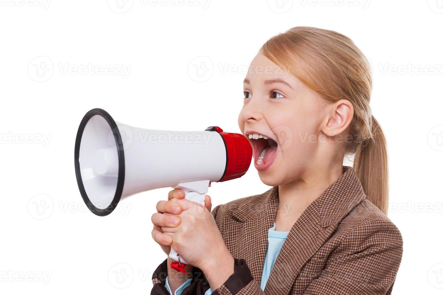 Announcing good news. Cheerful little girl in formalwear shouting at megaphone while standing isolated on white photo
