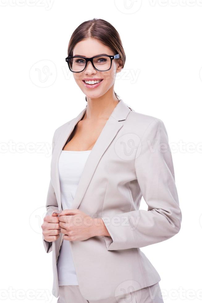 Beautiful and smart. Confident young businesswoman adjusting her jacket and smiling while standing against white background photo