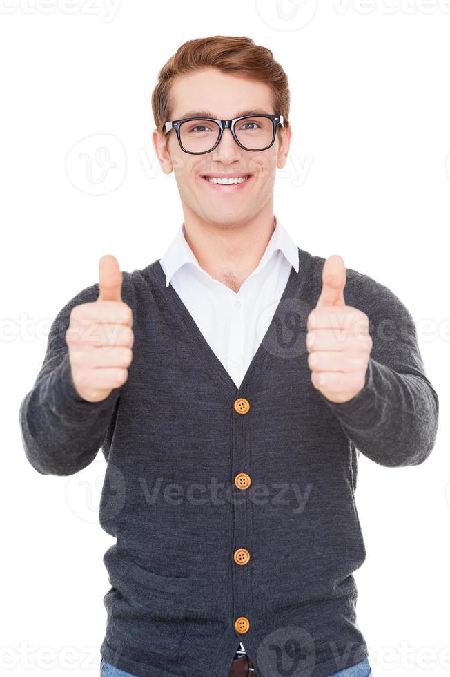 Success Cheerful young man showing his thumbs up and smiling while standing isolated on white photo