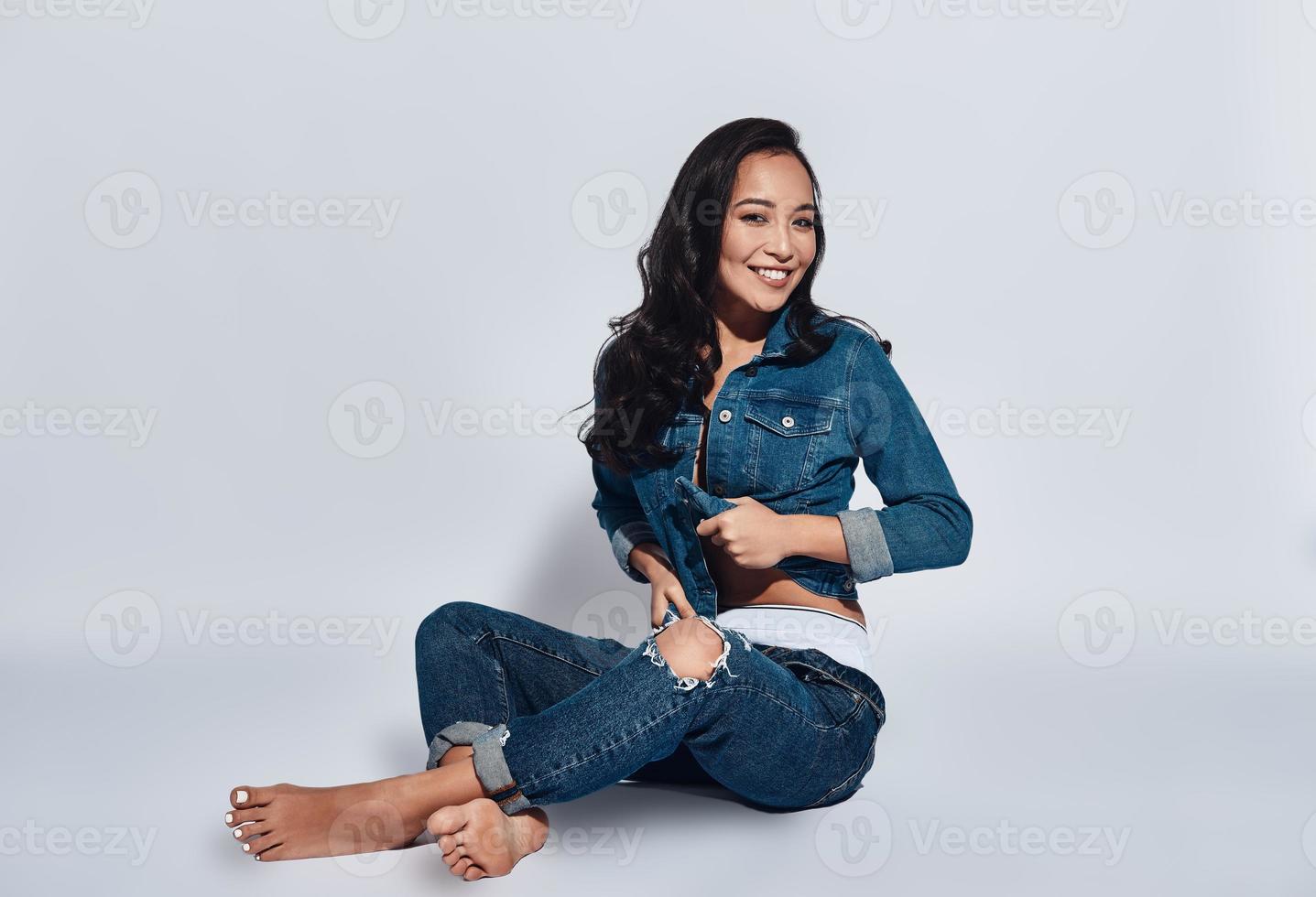 Sensual beauty. Attractive young woman looking at camera while sitting against grey background photo