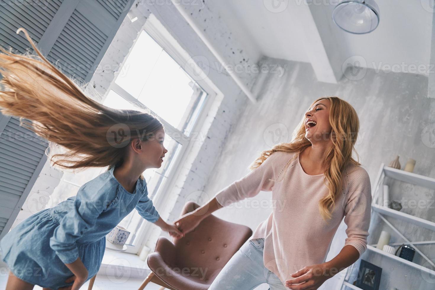 Happy to be together. Mother and daughter holding hands and smiling while dancing in bedroom photo