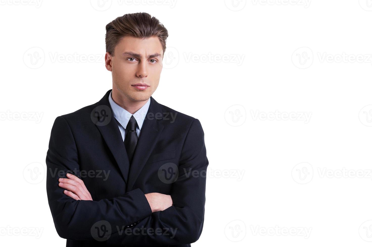 Portrait of success. Portrait of confident young man in formalwear keeping arms crossed and looking at camera while standing isolated on white photo