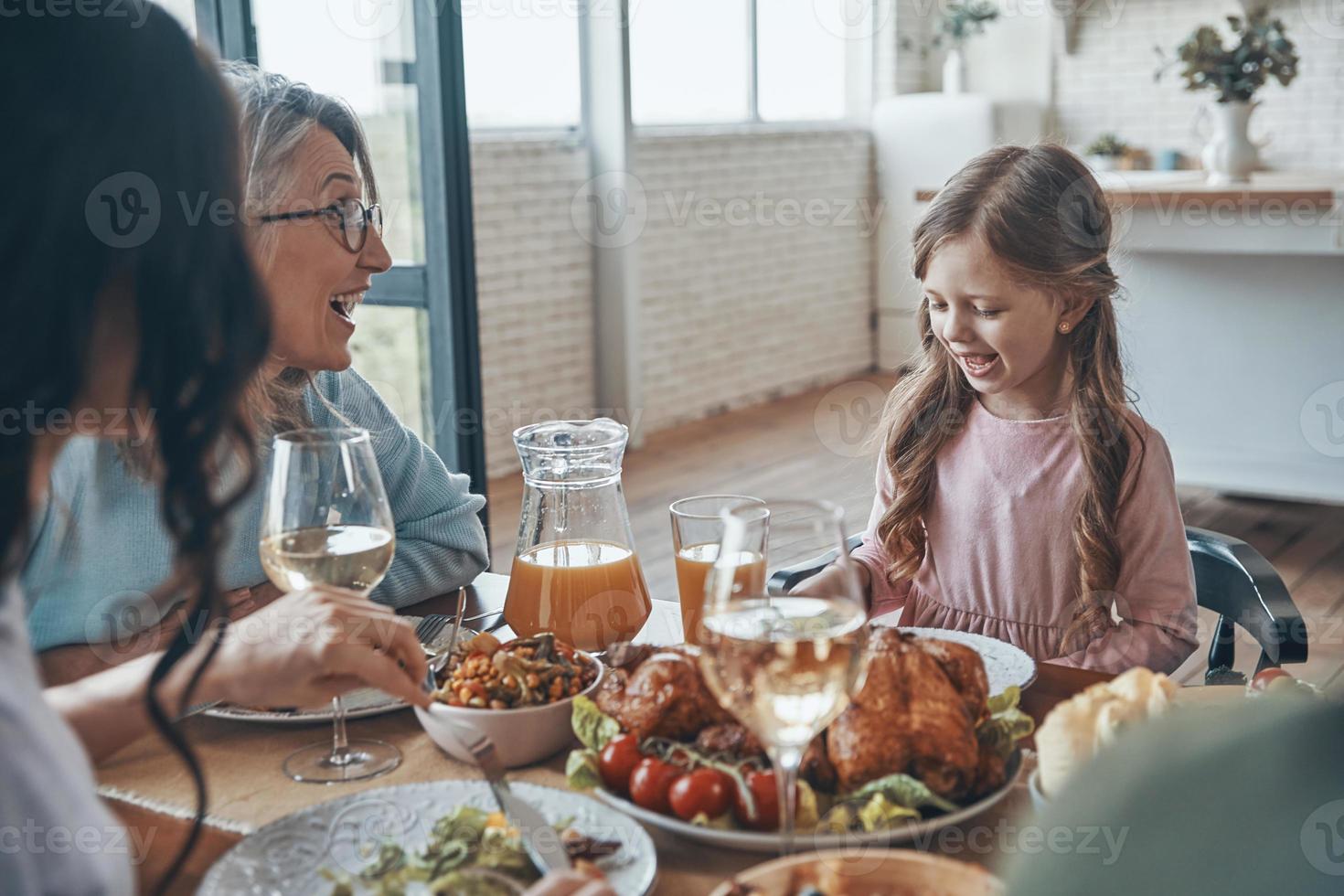 feliz familia multigeneracional comunicándose y sonriendo mientras cenamos juntos foto