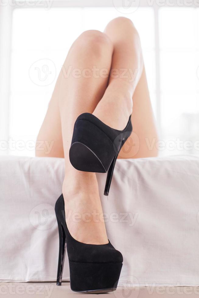 Piernas elegantes y hermosas. primer plano de hermosas piernas femeninas en zapatos negros de tacón alto en la cama foto