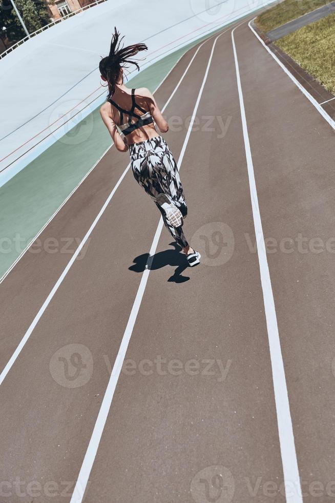 Ready to overcome any obstacle. Full length rear view of young woman in sports clothing jogging while exercising outdoors photo