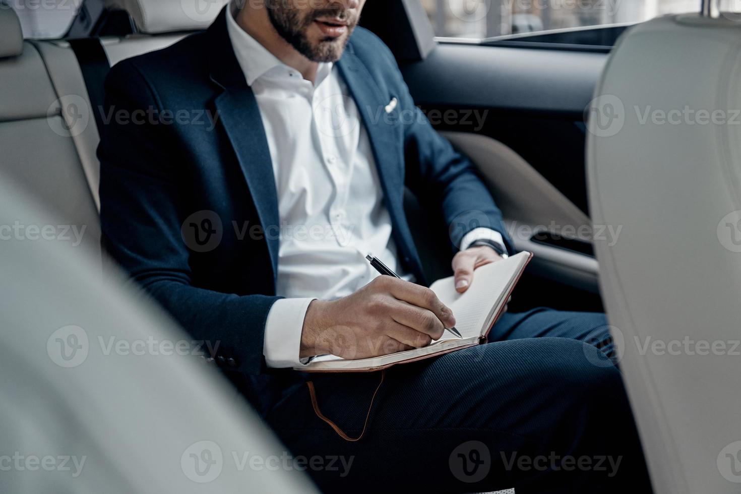 joven perfeccionista. primer plano de un joven con ropa formal escribiendo algo mientras está sentado en el auto foto