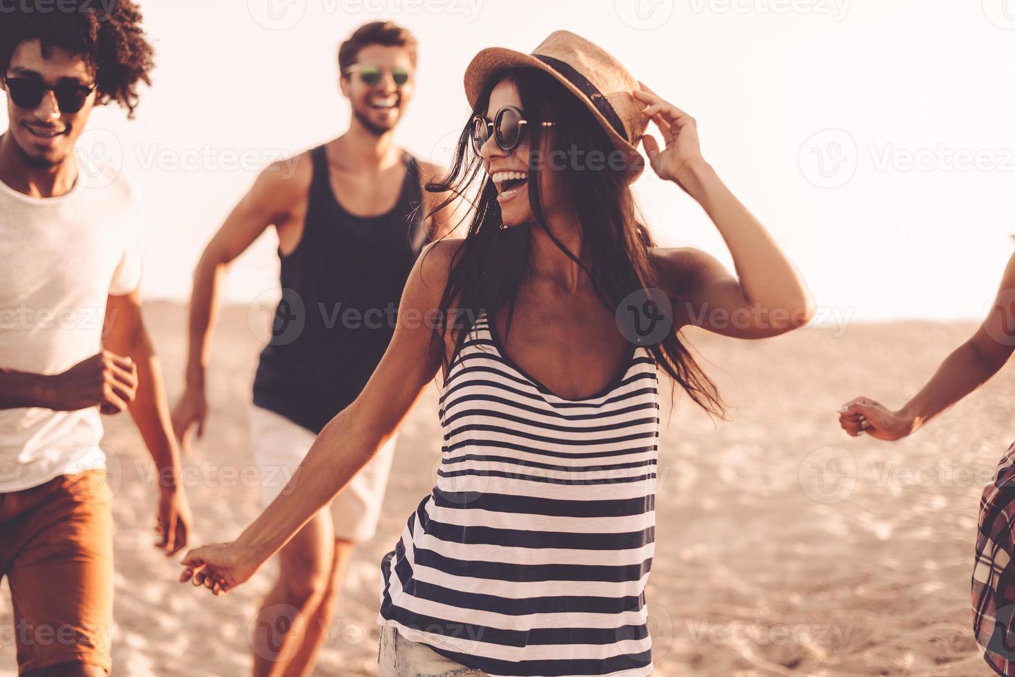 disfrutando de la juventud y la libertad. grupo de jóvenes alegres corriendo por la playa y luciendo felices foto