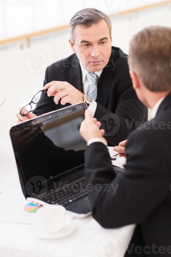 Business meeting. Business people in formalwear discussing something while sitting together at the table photo