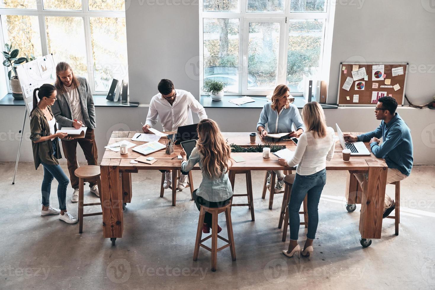 reunión de día. vista superior de los jóvenes modernos que se comunican mientras trabajan juntos en la sala de juntas foto