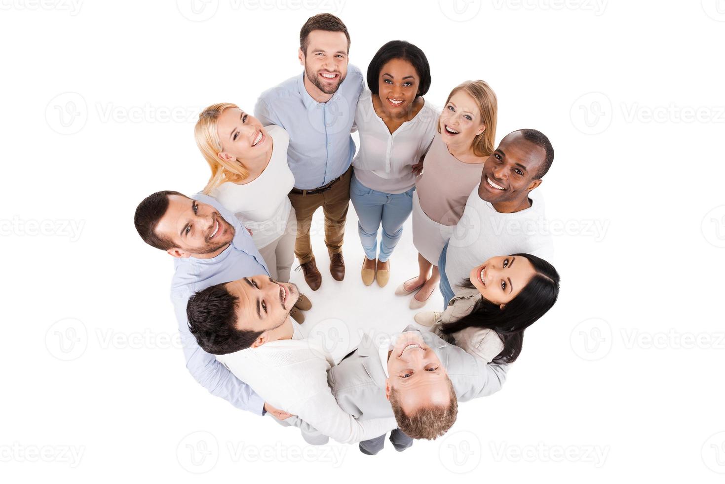 Happy united team. Top view of positive diverse group of happy people in smart casual wear bonding to each other and standing in circle photo