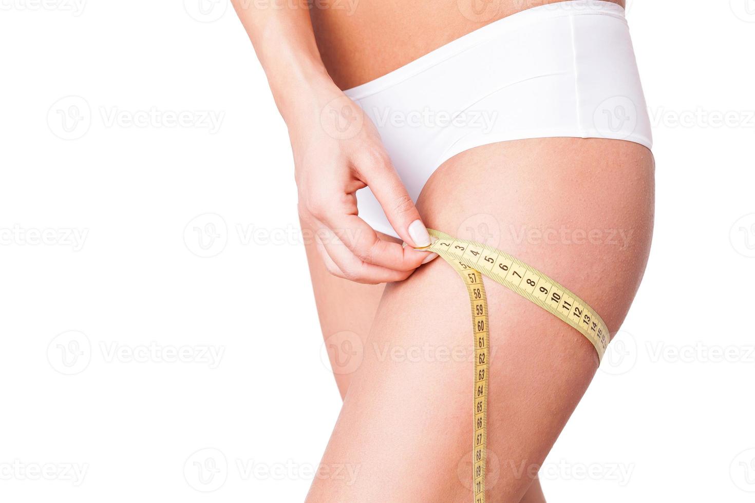 Woman measuring haunch. Cropped image of woman in white panties measuring her haunch while standing isolated on white photo