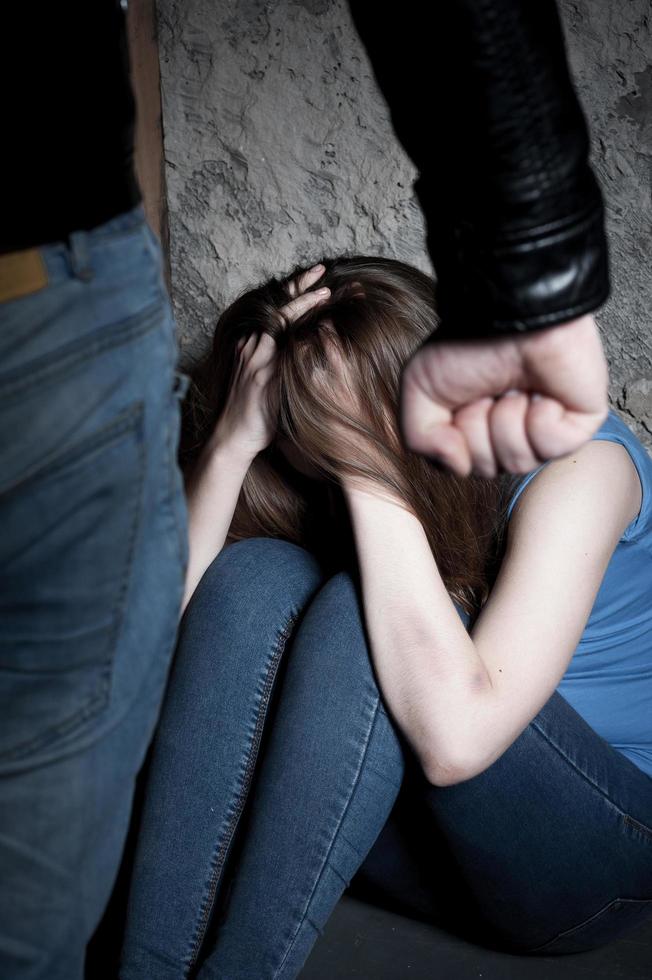 Violence. Young woman crying and holding hands in hair while sitting on the floor photo