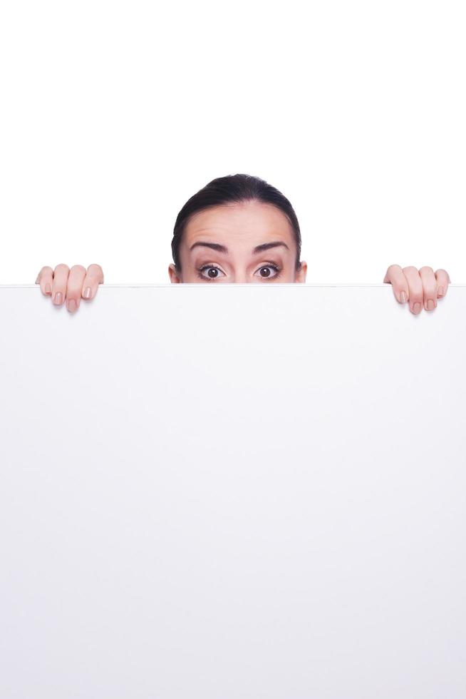 Looking out of copy space. Shocked young woman looking out of copy space while isolated on white photo