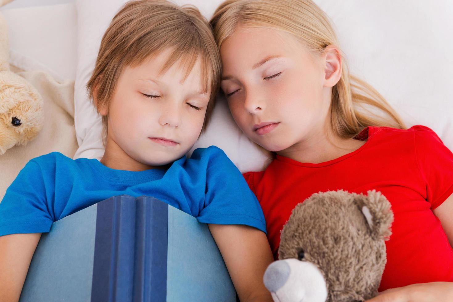 Tired after active day. Top view of two cute children sleeping while lying in bed together photo