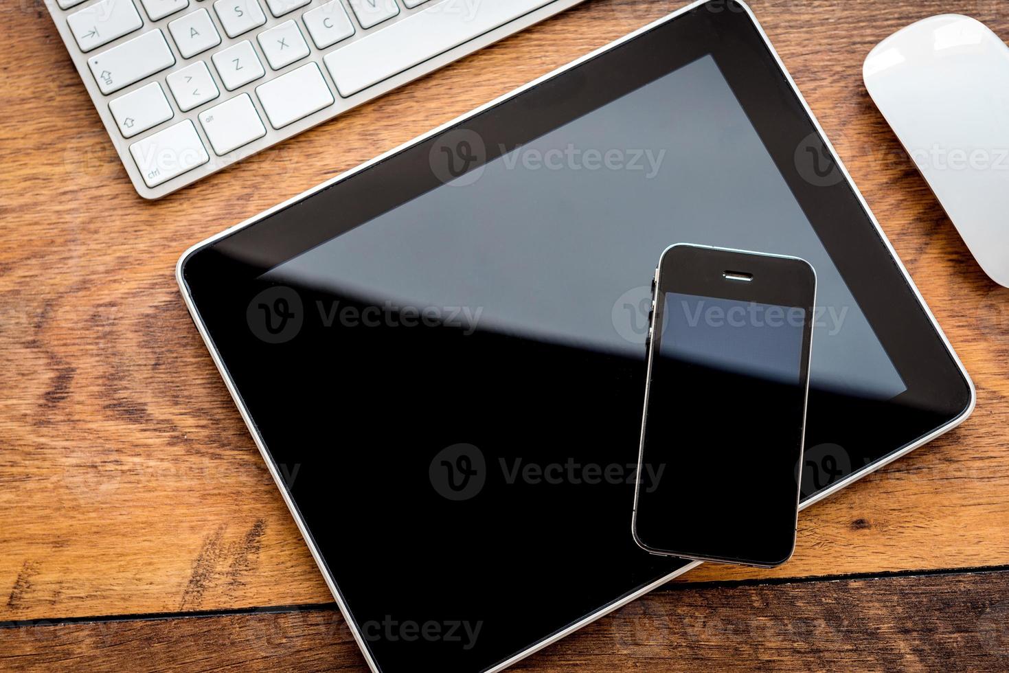 Full interaction. Top view of digital tablet and mobile phone laying on wooden table photo