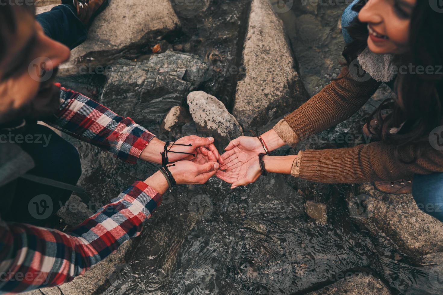 Close up top view of young smiling couple washing hands in the river while hiking in mountains photo