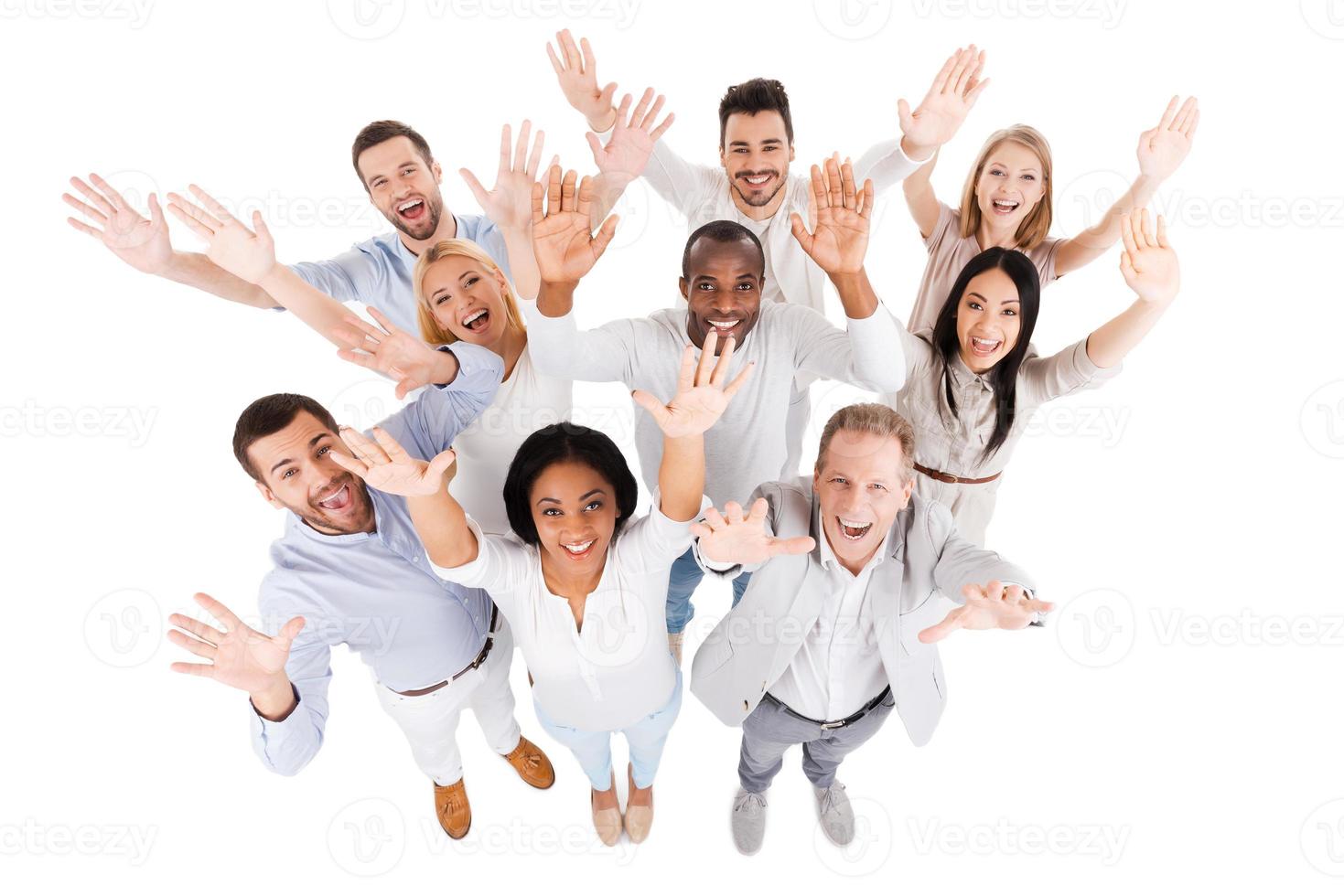 Successful business team. Top view of positive diverse group of people in smart casual wear looking at camera and stretching out their hands while standing close to each other photo