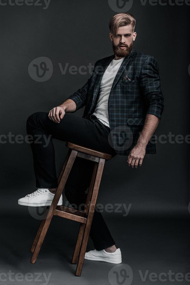 Enjoying his casual style. Full length of confident young man looking at camera while posing against grey background photo