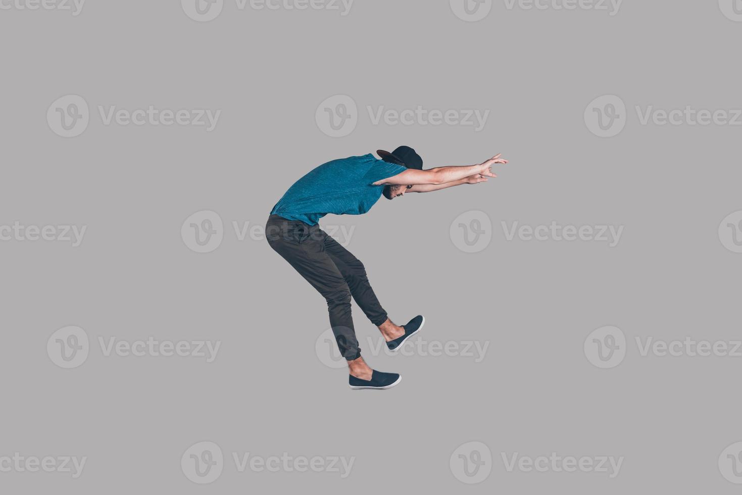 In motion. Mid-air shot of handsome young man in cap jumping and gesturing against background photo