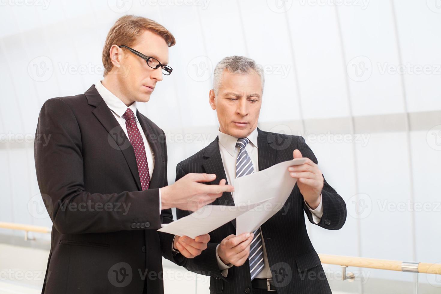 Business discussion. Two confident business men discussing something while holding papers in their hands photo