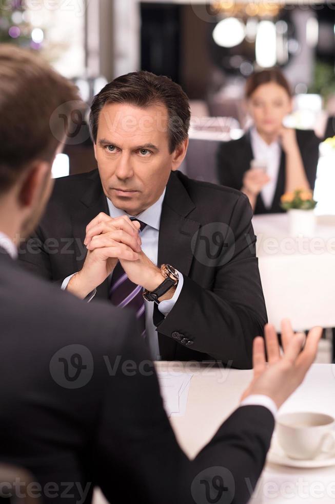 Business meeting. Business people in formalwear discussing something while sitting at the restaurant photo