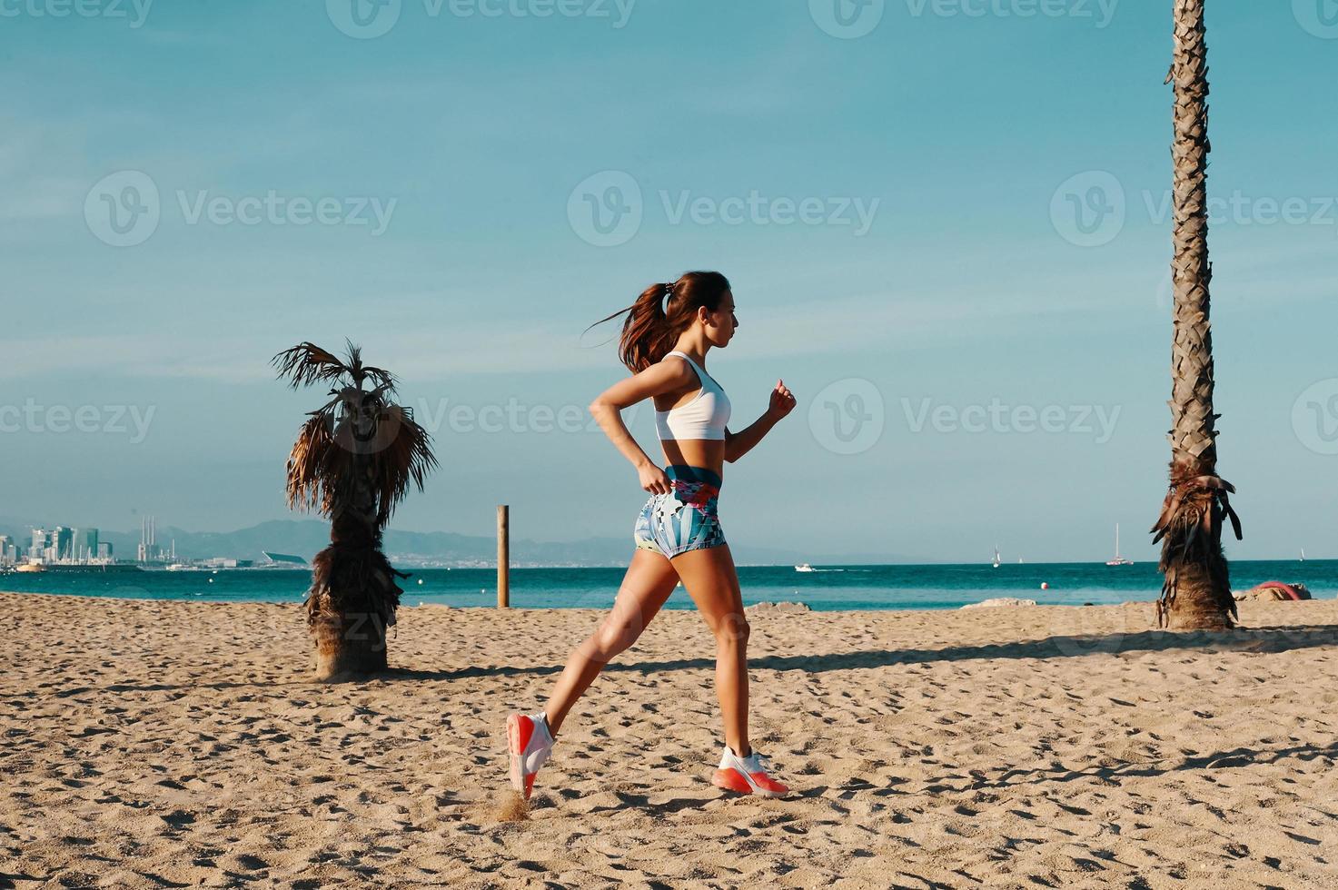 siempre en forma. toda la longitud de una hermosa joven con ropa deportiva trotando mientras hace ejercicio al aire libre foto