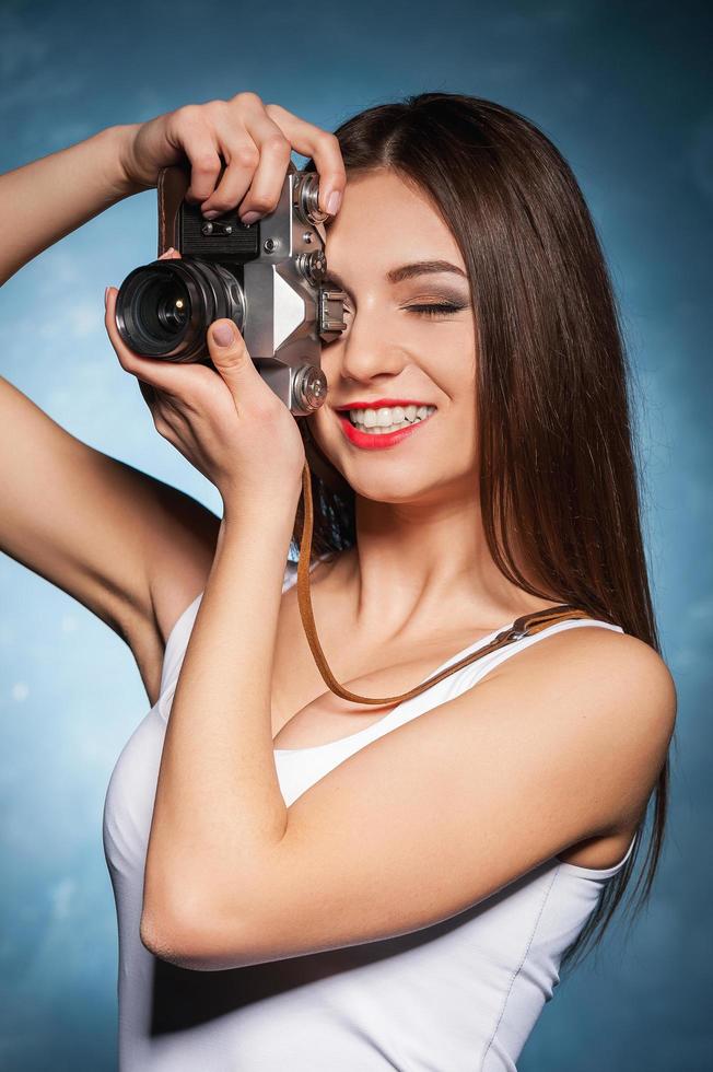 le gusta fotografiar. hermosa joven enfocando con la cámara y sonriendo foto