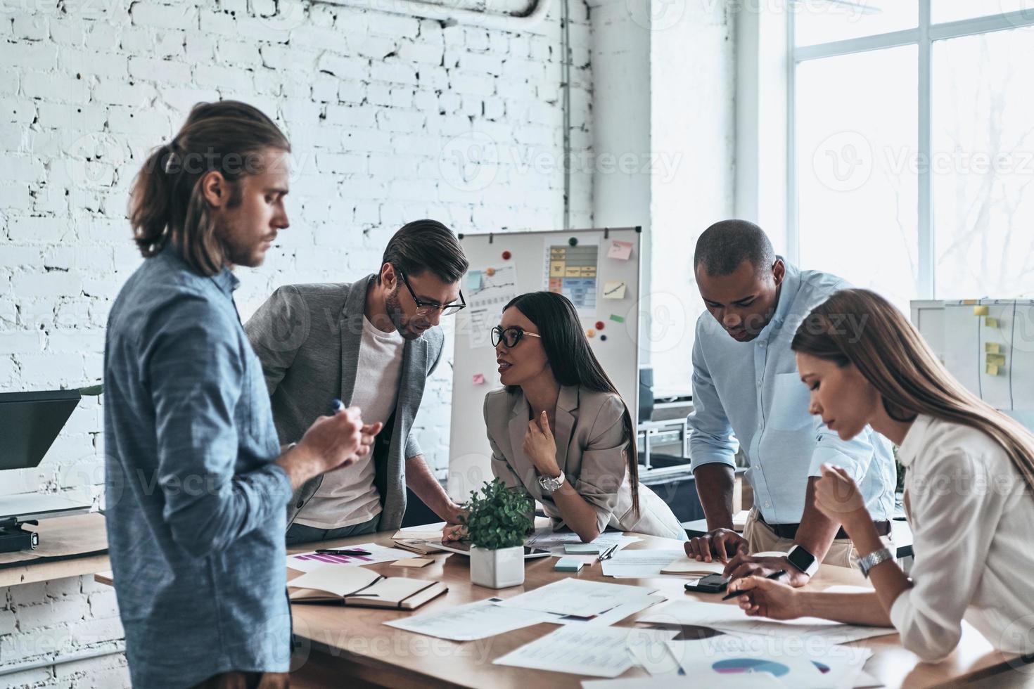 discutiendo estrategia. grupo de jóvenes empresarios que trabajan y se comunican mientras pasan tiempo en la oficina foto