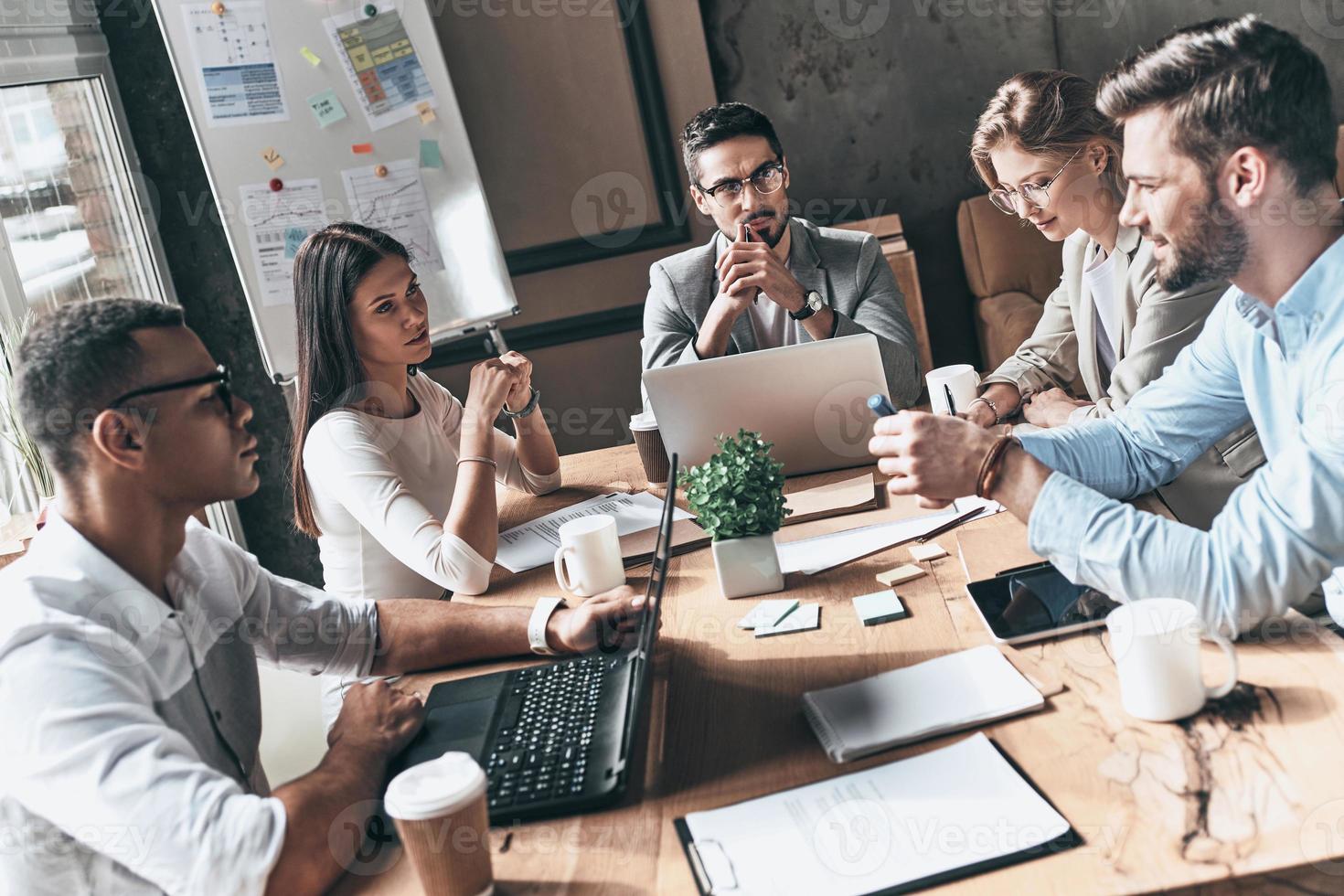 compartiendo ideas. vista superior de los jóvenes modernos con ropa informal inteligente discutiendo negocios mientras trabajan en la oficina creativa foto