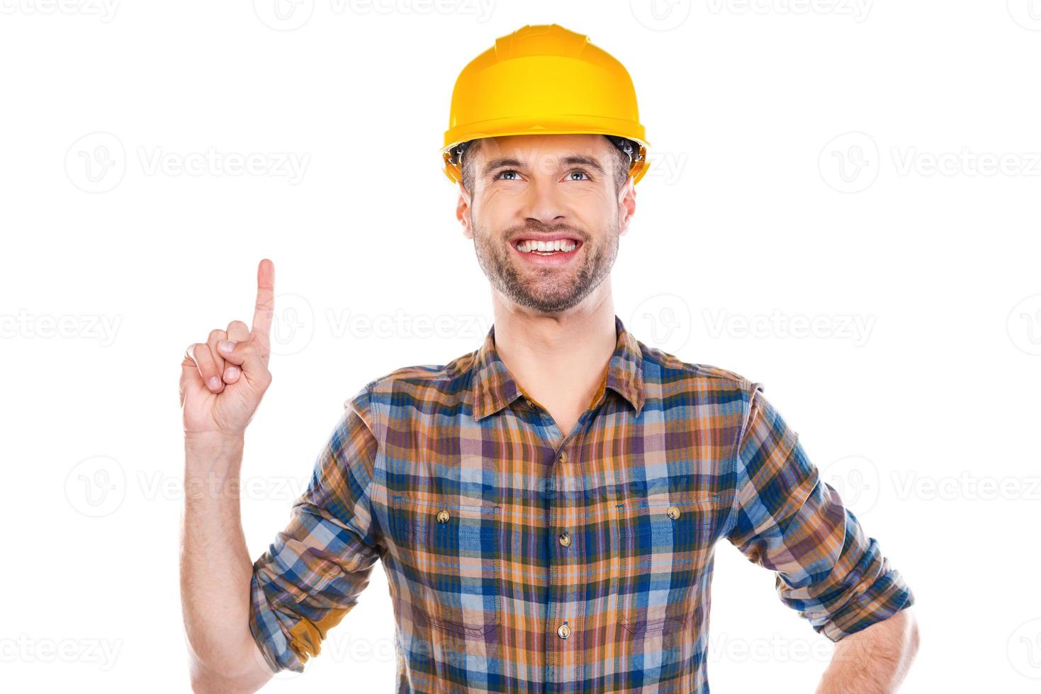 Look at that Confident young male carpenter pointing up and smiling while standing against white background photo