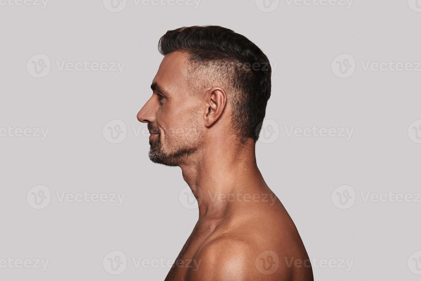 Freshness. Side view of good looking young man smiling while standing against grey background photo