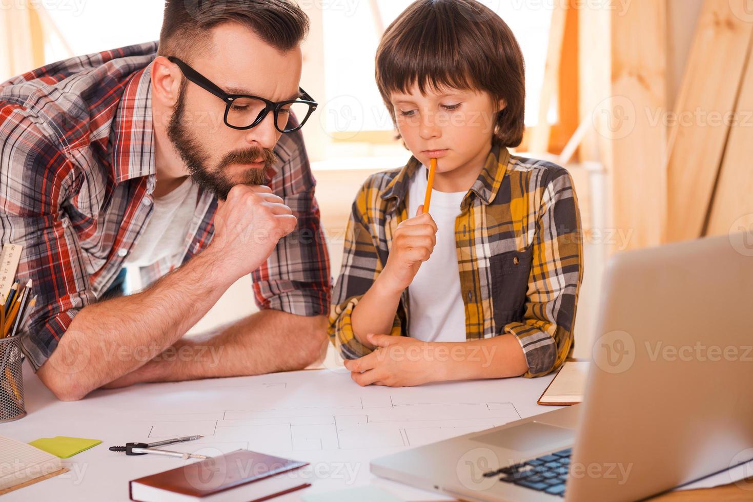 Family brainstorming. Thoughtful young man and his sonworking together while sitting at working place photo