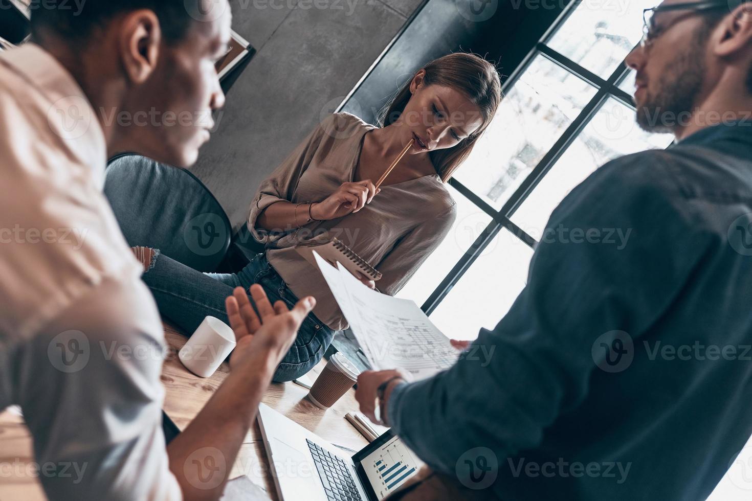 Group of young people in smart casual wear discussing business while working in the office photo