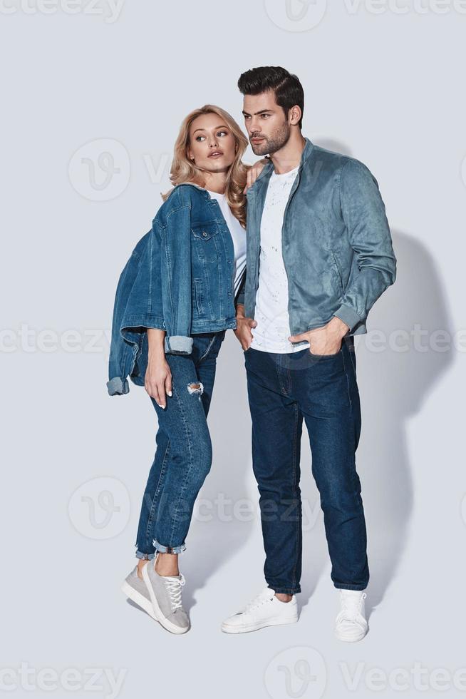 All about fashion. Full length of beautiful young couple bonding while standing against grey background photo
