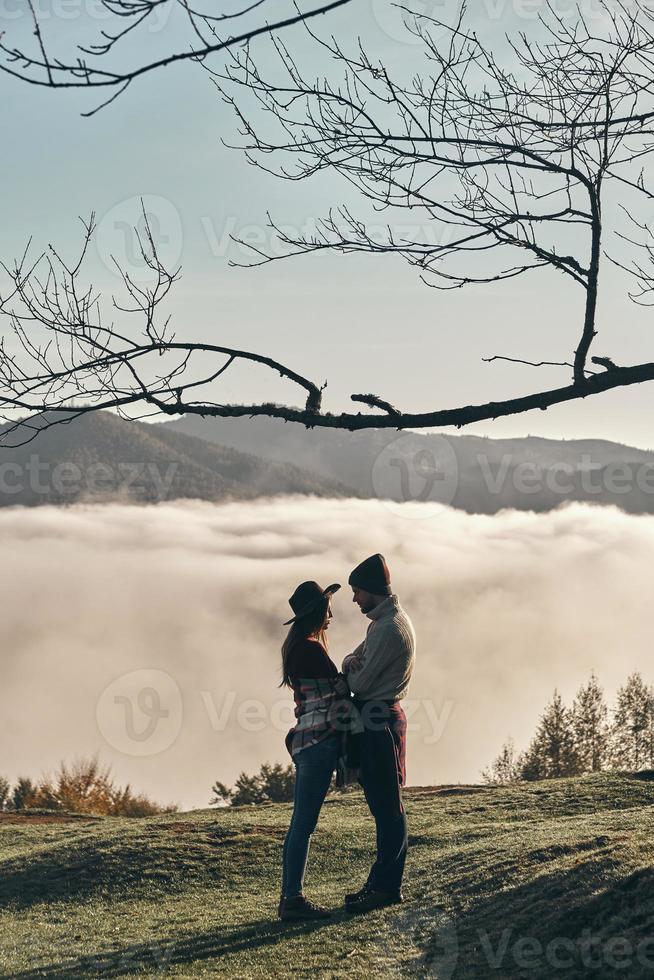 They found love. Full length of young couple standing face to face while enjoying the perfect view of mountain range photo