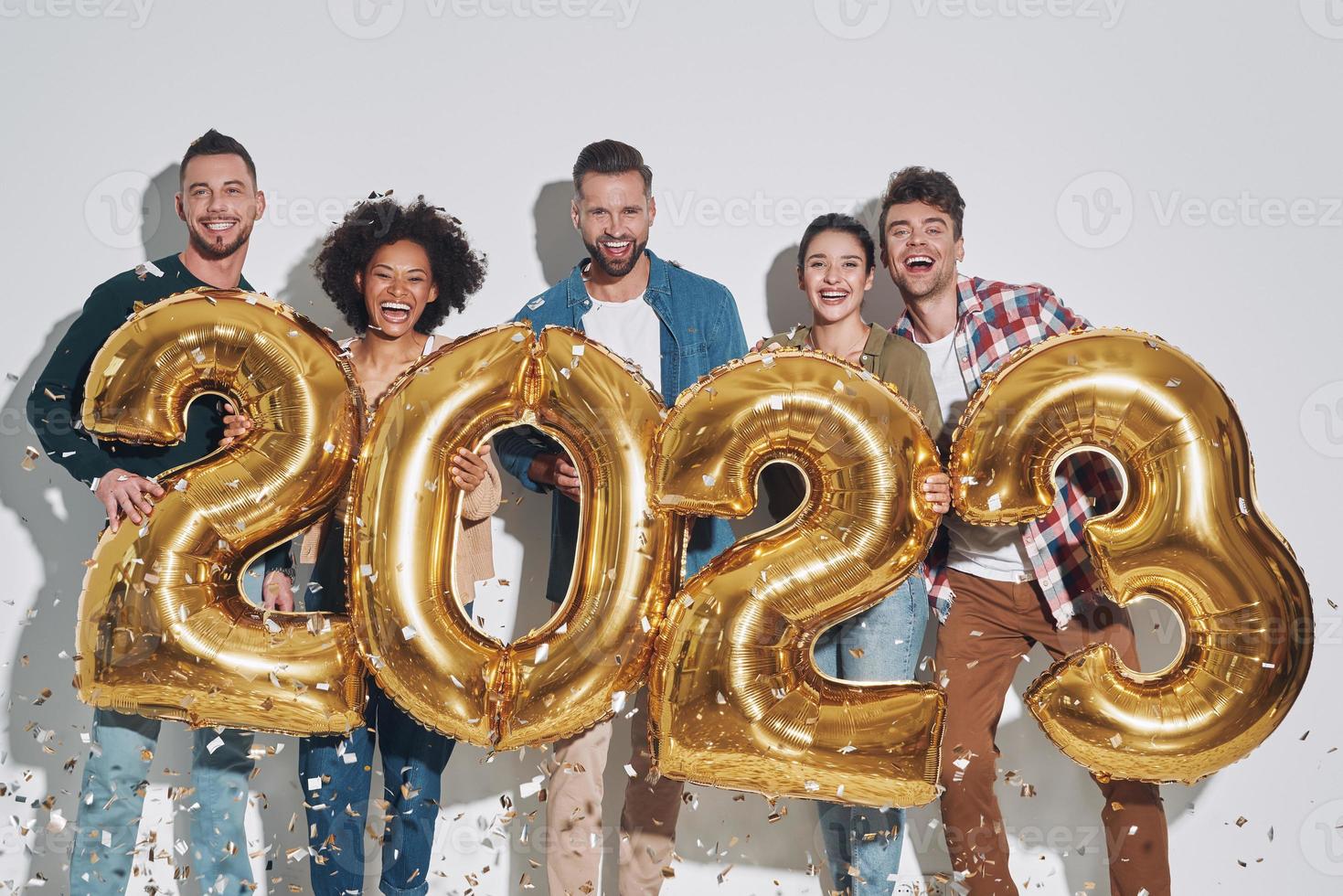 grupo de jóvenes hermosos con ropa informal que llevan números dorados y sonríen foto