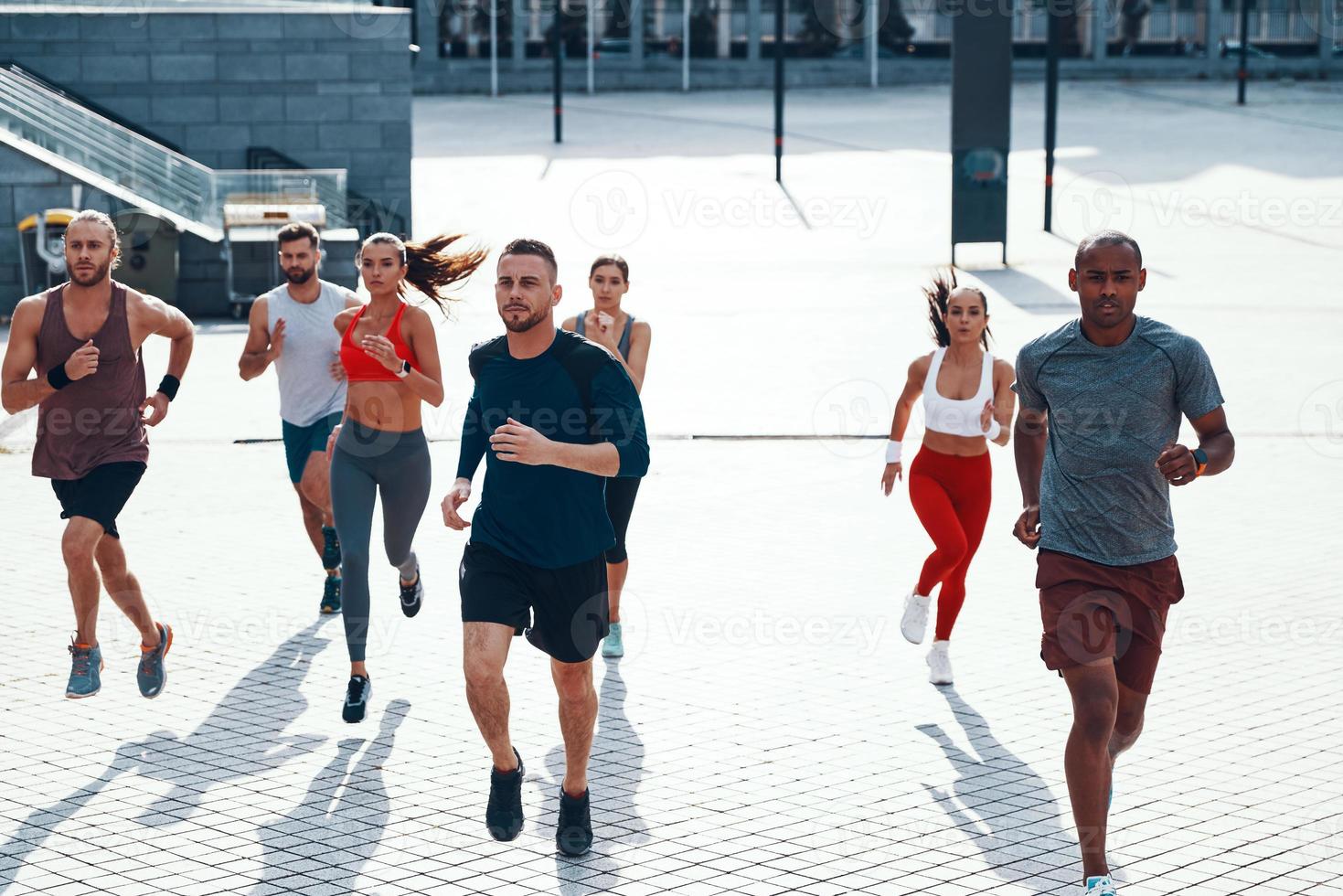 vista superior de personas con ropa deportiva trotando mientras hacen ejercicio en la acera al aire libre foto