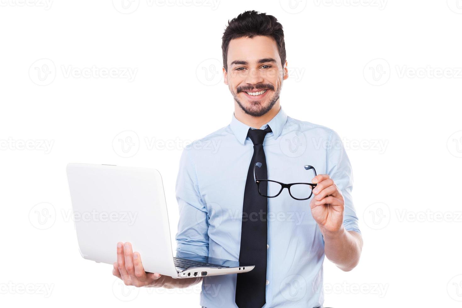 How may I help you Handsome young man in shirt and tie holding laptop and smiling while standing against white background photo