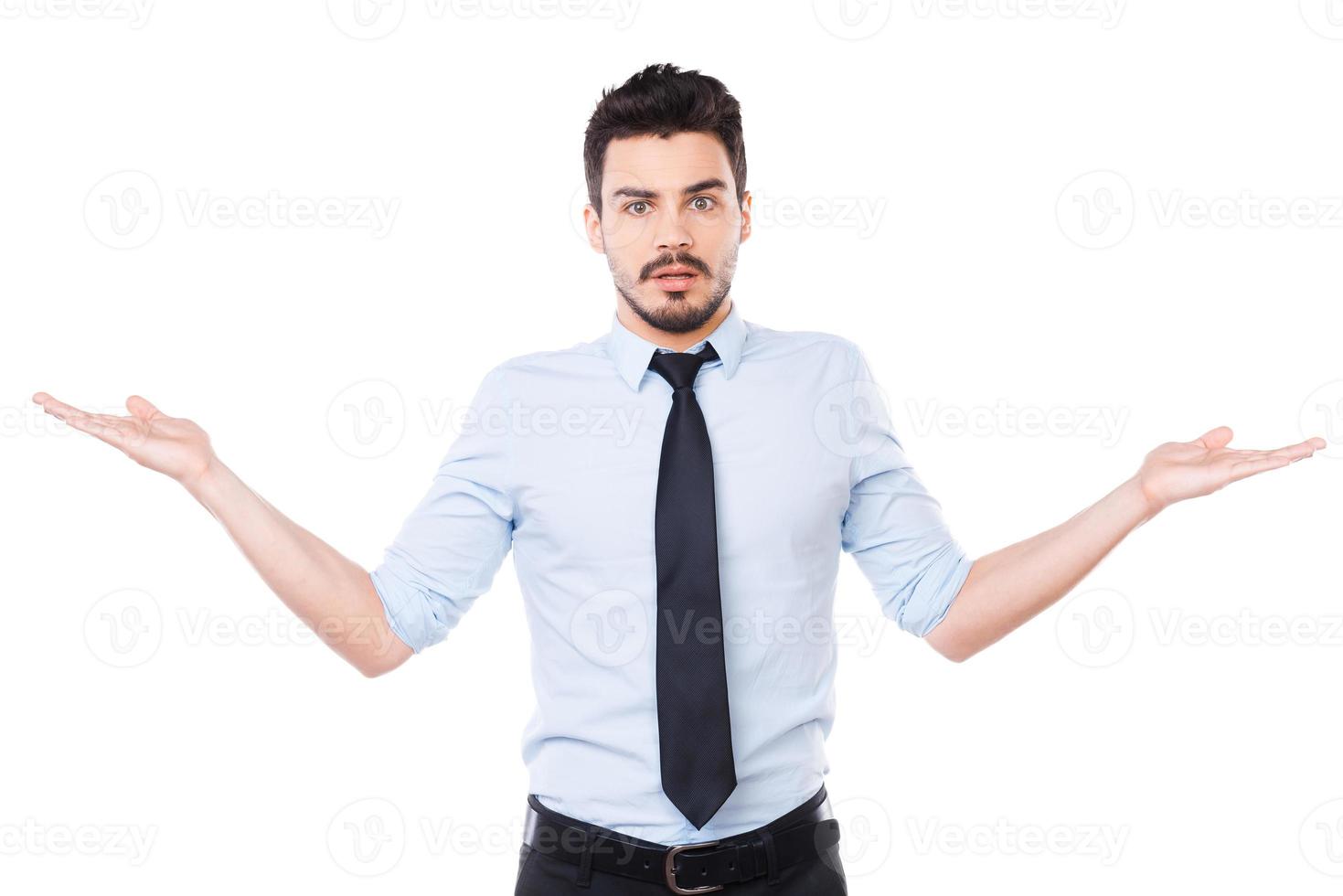 So hard to choose Frustrated young man in shirt and tie holding copy spaces in both hands and looking at camera while standing against white background photo