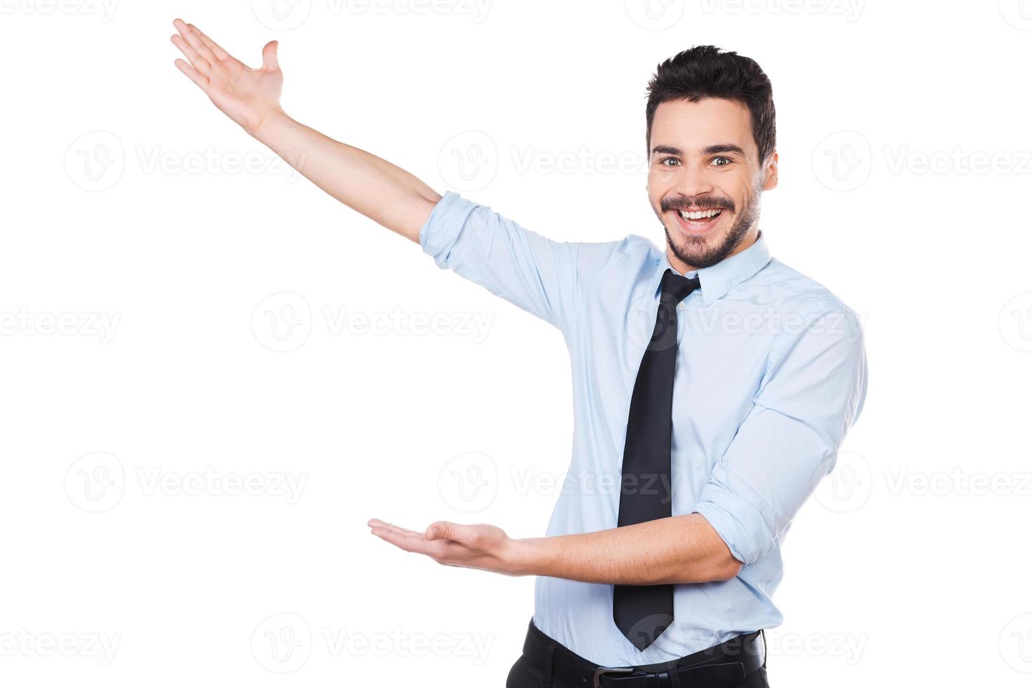 It is unbelievable Happy young man in shirt and tie pointing away and smiling while standing against white background photo