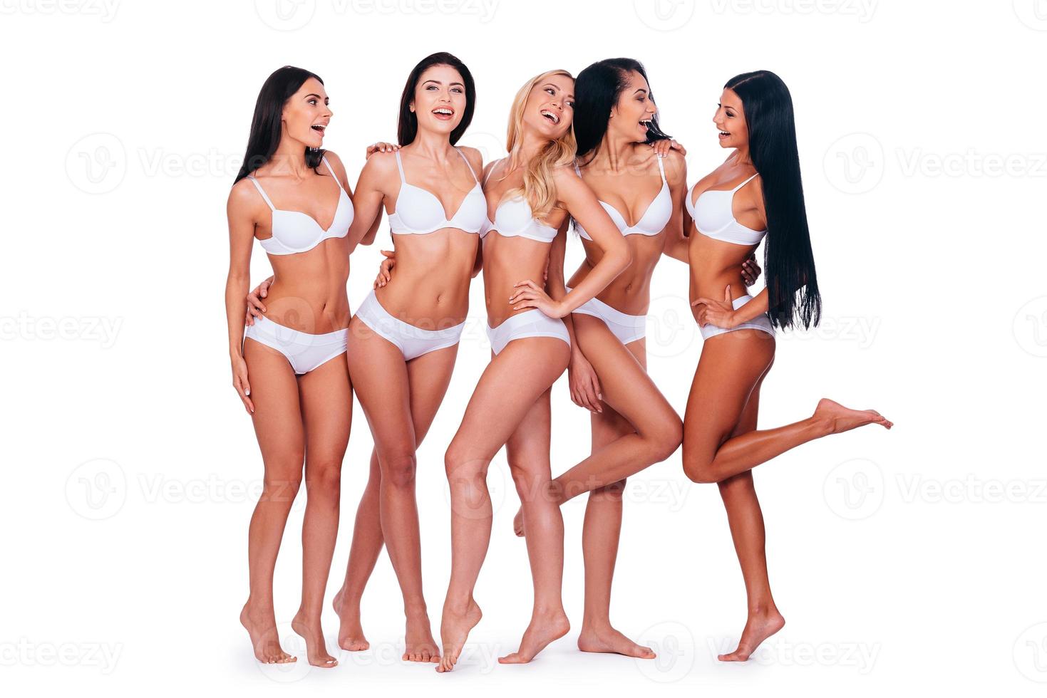 chicas divirtiéndose. Longitud total de cinco hermosas mujeres en lencería posando y luciendo naturales mientras están juntas contra el fondo blanco foto