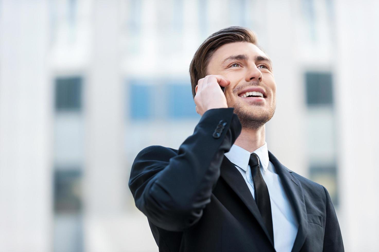 Hombre de negocios exitoso. jóvenes alegres en ropa formal hablando por teléfono móvil y sonriendo foto