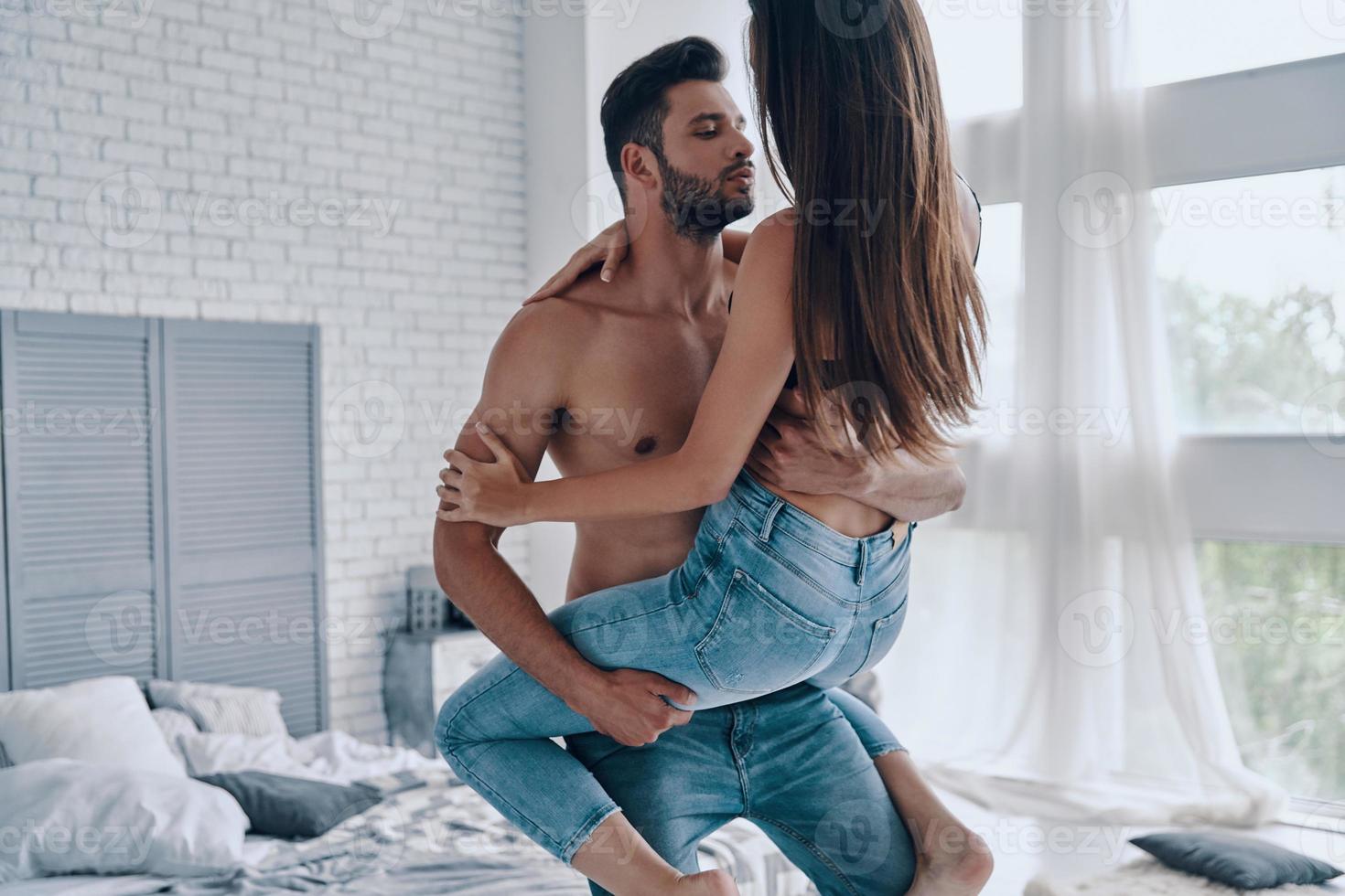 Happy couple at home. Beautiful young couple embracing while standing in the bedroom photo
