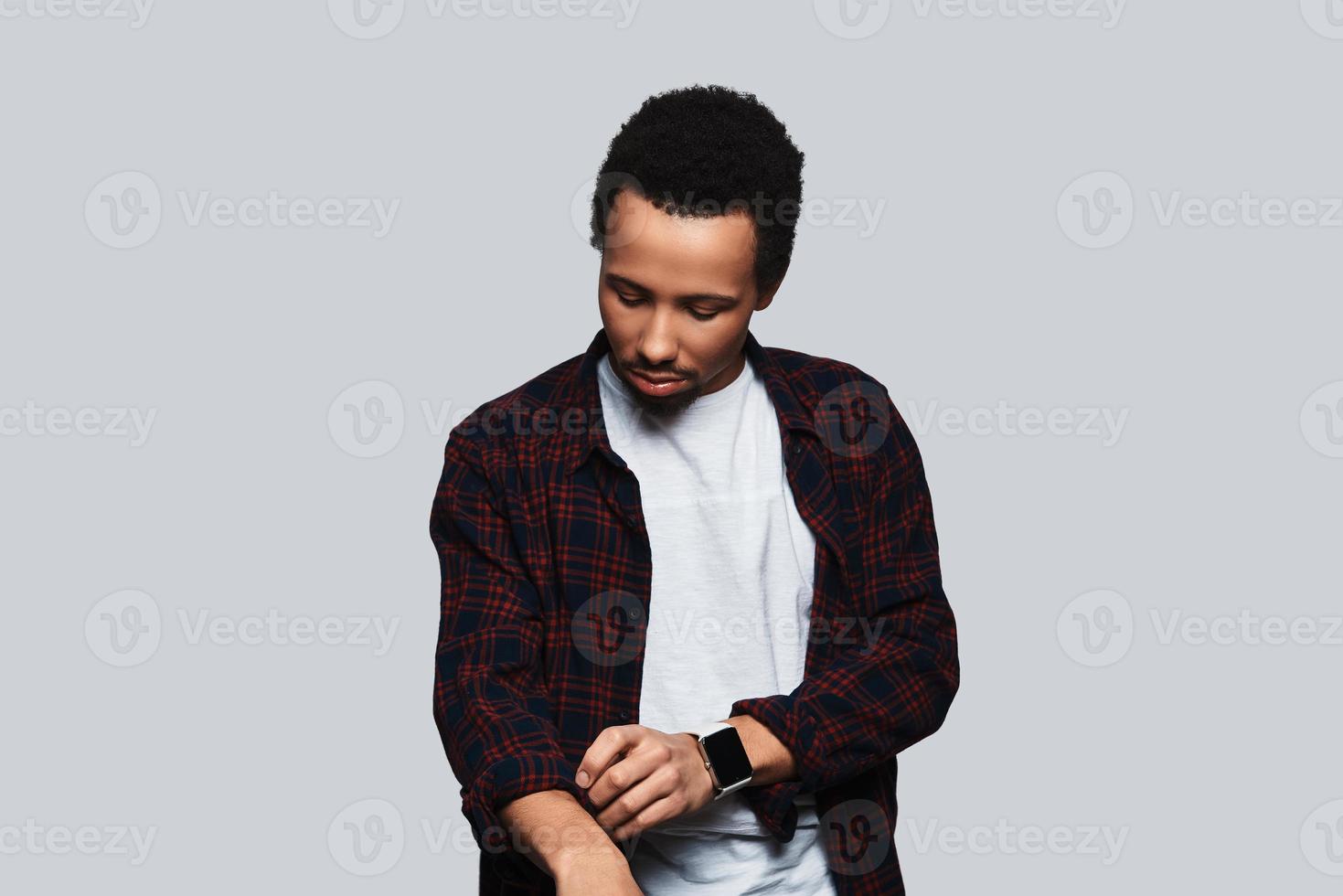 Everything must be perfect. Handsome young man in casual clothing adjusting sleeve while standing against grey background photo