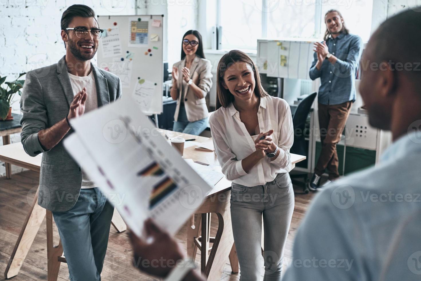 Great presentation. Group of business people clapping and smiling while working in the board room photo