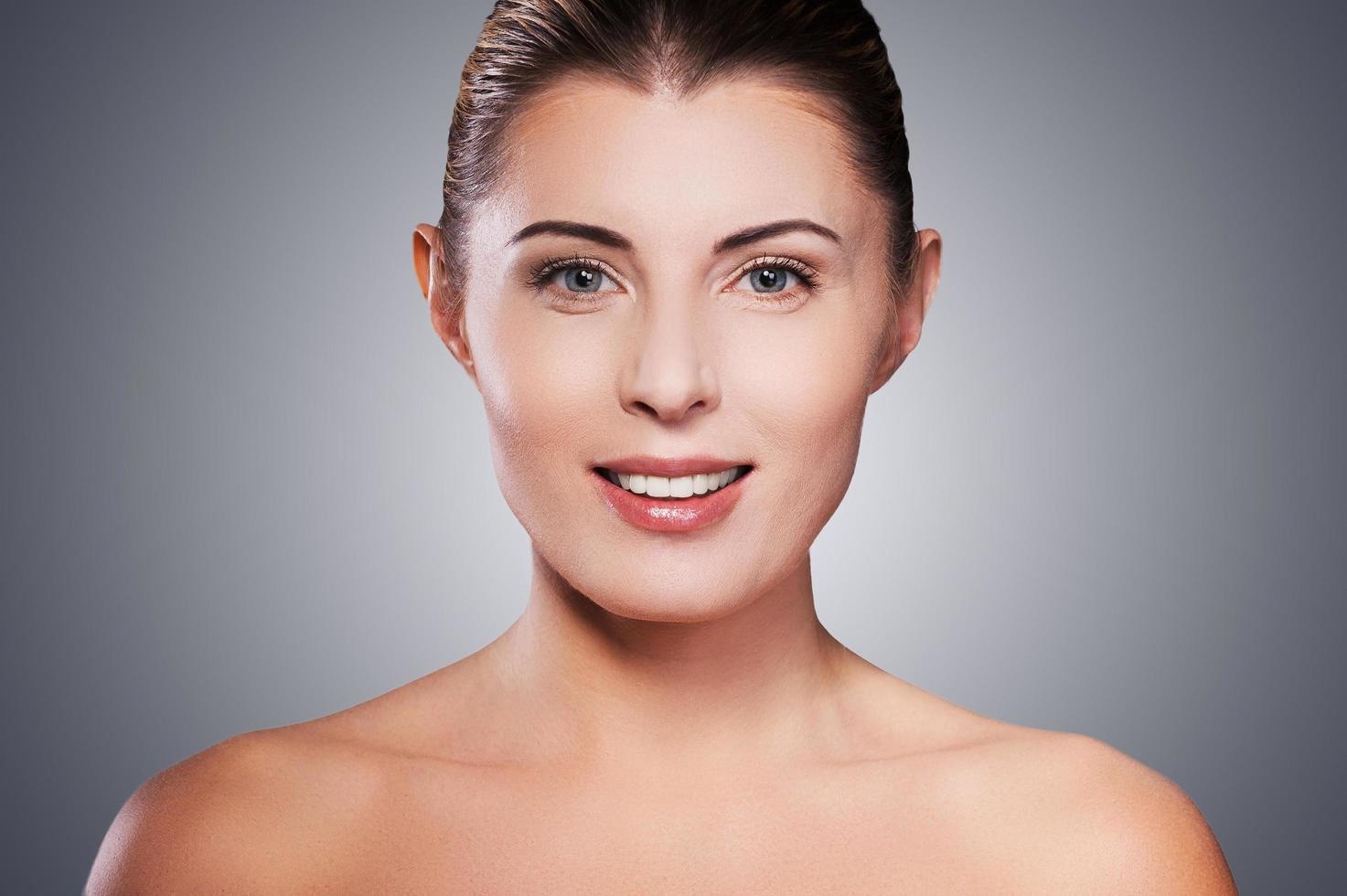 Natural beauty. Portrait of shirtless mature woman smiling while standing against grey background photo