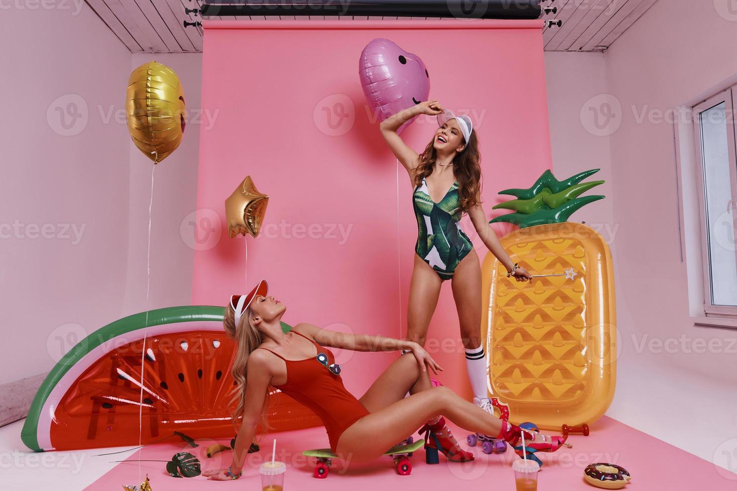 Feeling free and happy. Playful young women in swimwear going crazy while posing against pink background photo